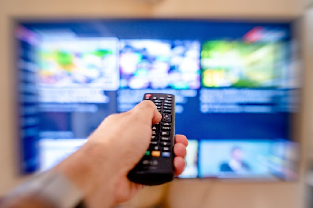 Dłoń z pilotem na tle telewizora w salonie