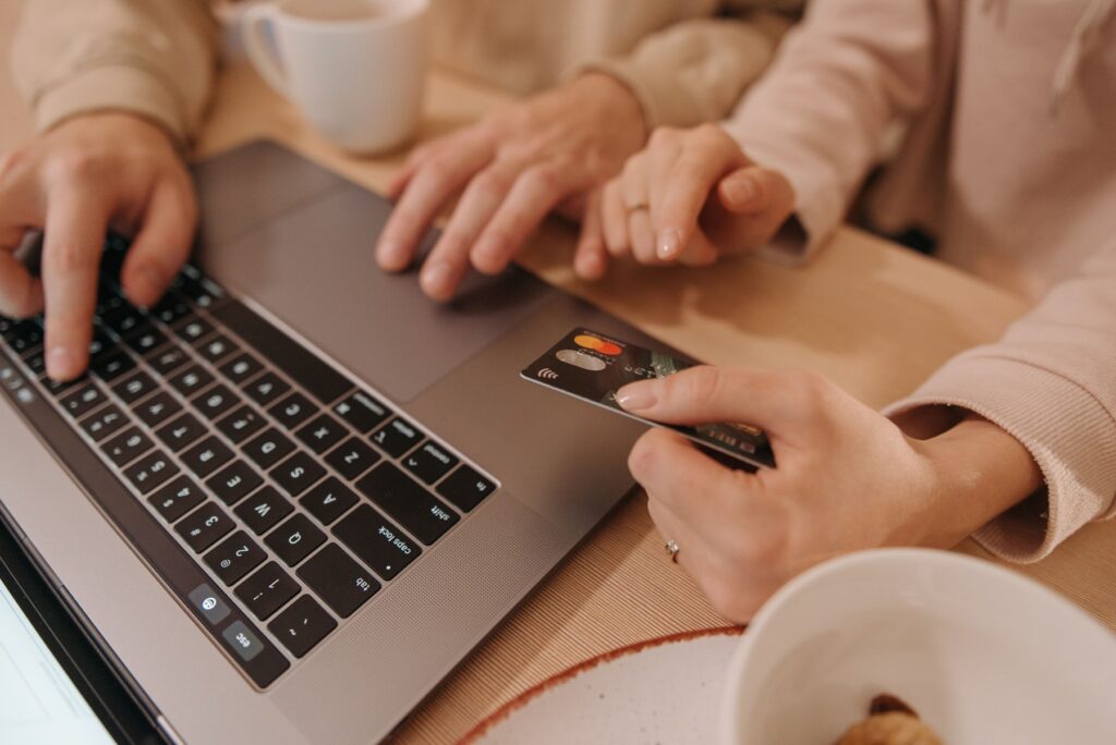 Dłonie przy laptopie i karcie podczas zakupów online